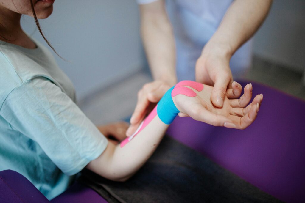 Physiotherapeut behandelt das Handgelenk einer Patientin mit Tape nach einer Verletzung